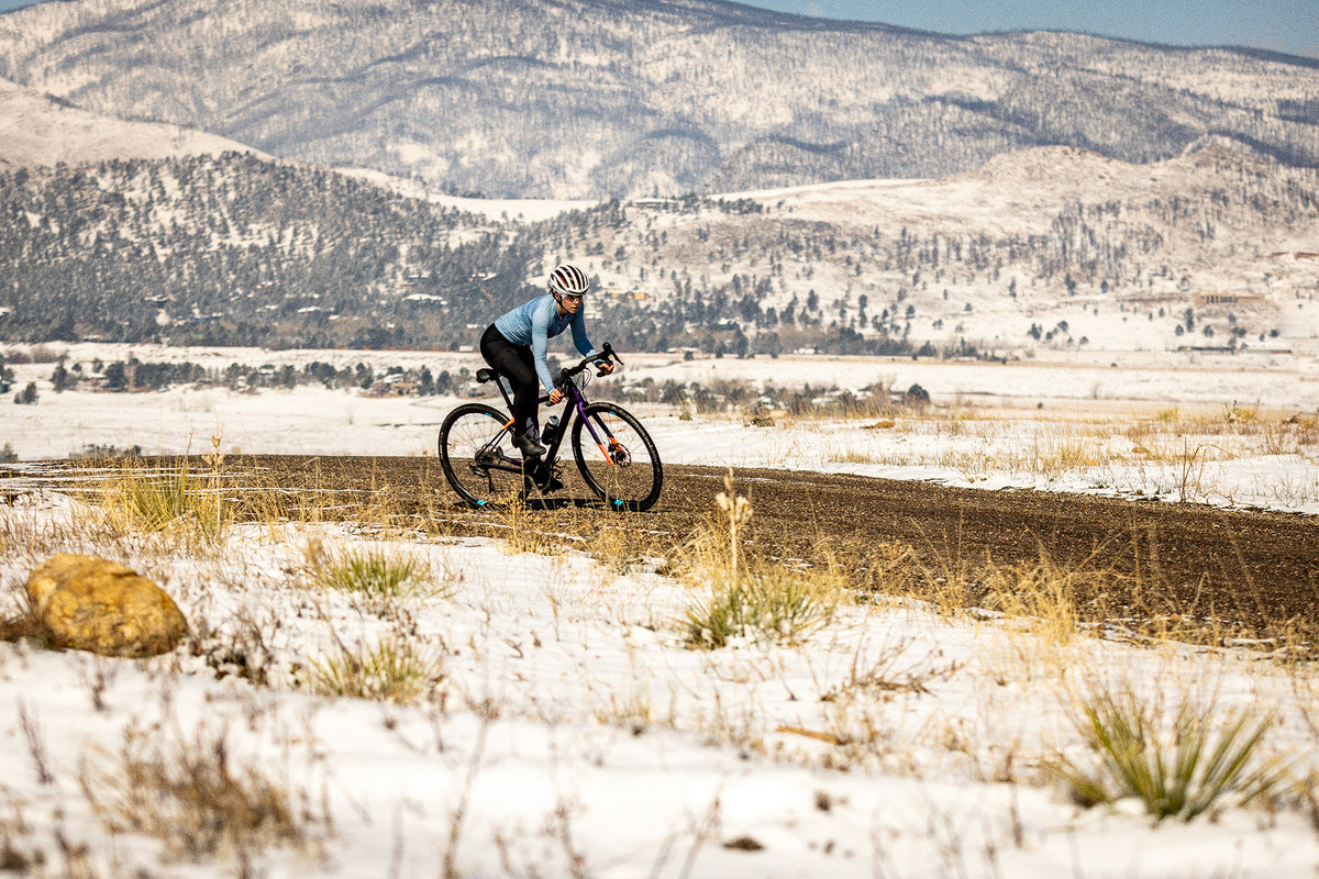 Biker riding gravel with snowy mountains